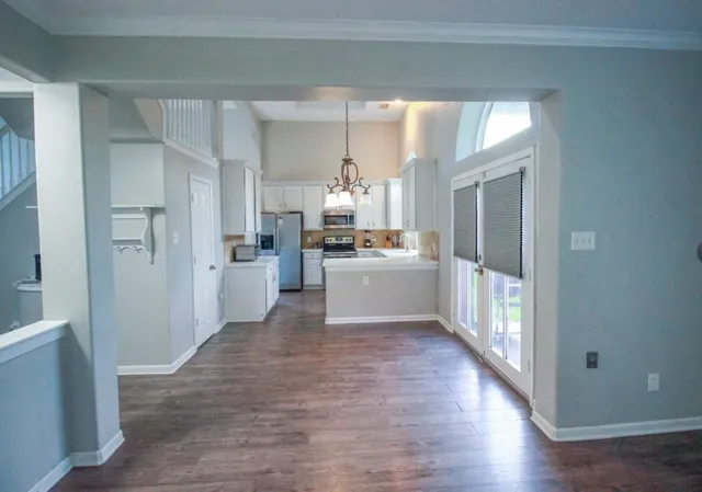 a kitchen with white cabinets and wooden floor