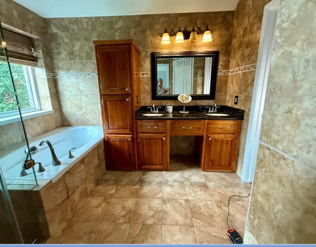 a bathroom with a tub sink and mirror