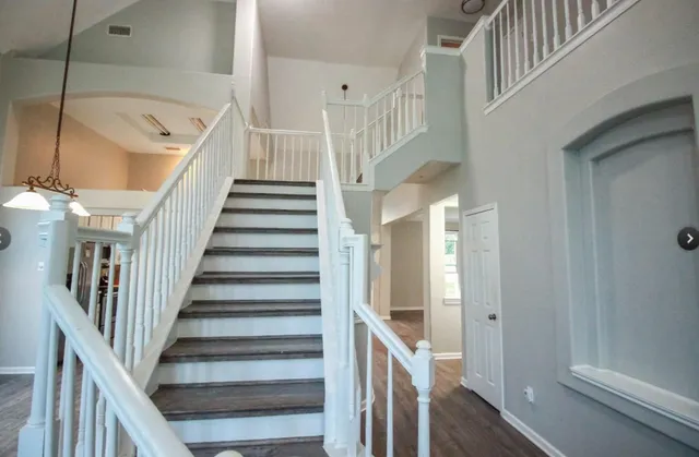 a view of staircase with lots of frames on wall and wooden floor