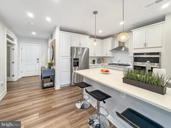 a kitchen with a sink dishwasher a refrigerator with white cabinets and wooden floor
