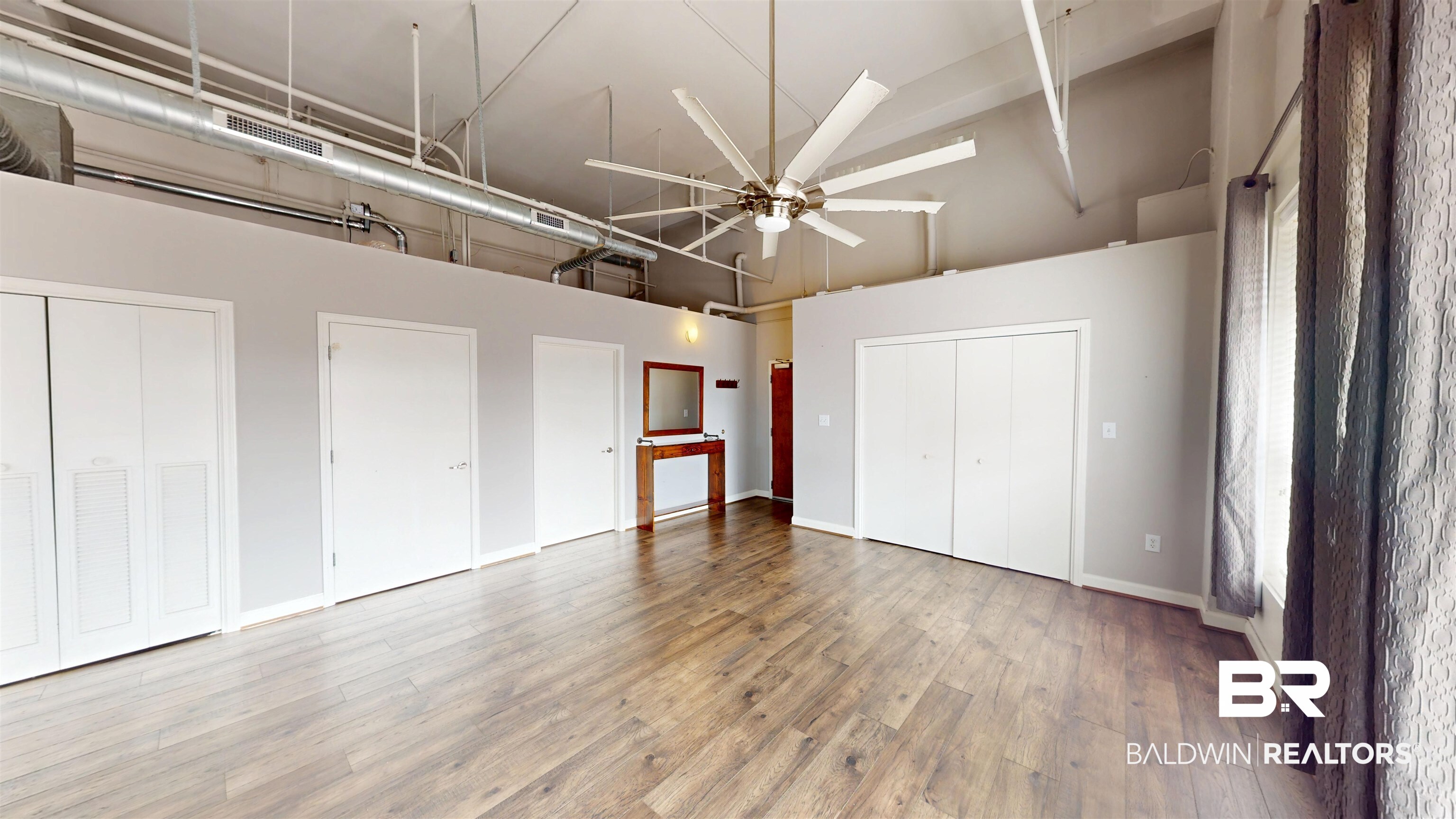 308 St Louis Street, Unit 101 Mobile, AL 36602 - Photo 20 of 30 Unfurnished bedroom with high vaulted ceiling, multiple closets, light wood-style floors, and a ceiling fan