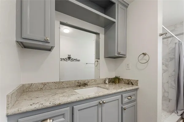 a bathroom with a granite countertop sink and a mirror