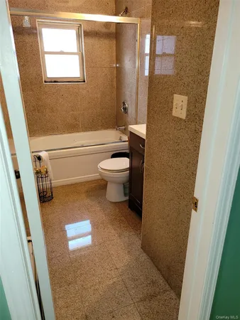 a bathroom with a granite countertop toilet a sink a mirror and shower