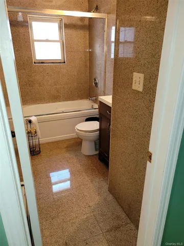 a bathroom with a granite countertop toilet a sink a mirror and shower