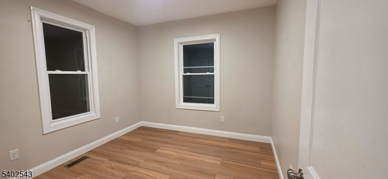 115 Wallington Avenue Wallington, NJ 07057 - Photo 7 of 13 a view of an empty room with wooden floor and a window