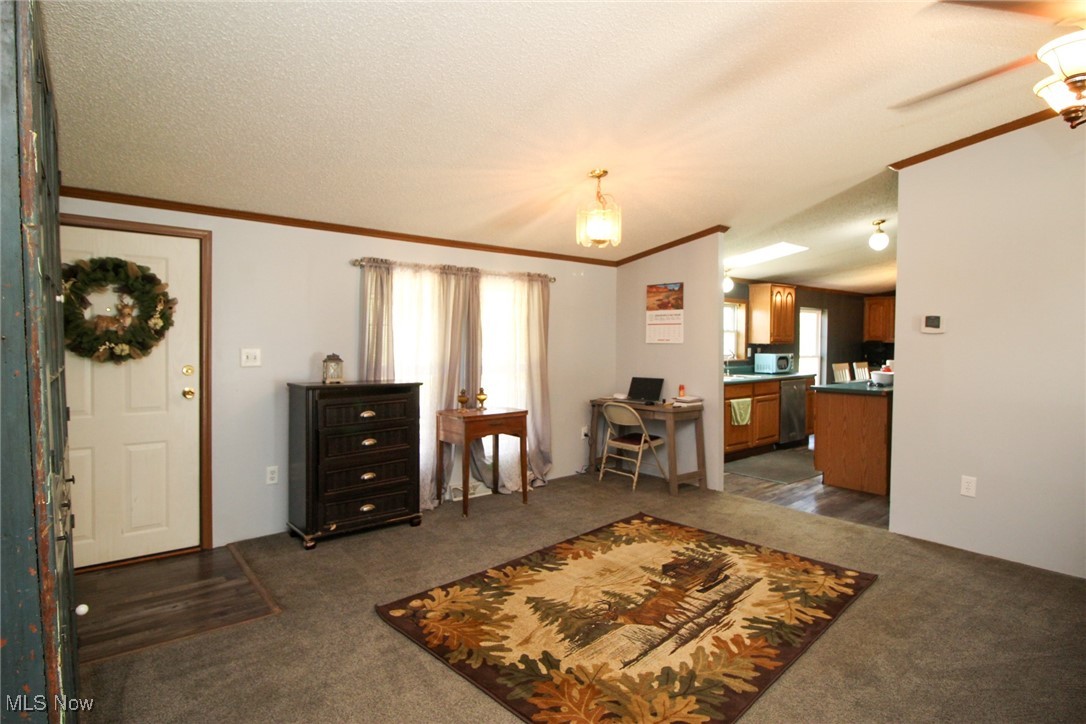 1798 Campbell Road Southwest New Philadelphia, OH 44663 - Photo 11 of 50 Living room featuring ceiling fan, a textured ceiling, and dark carpet