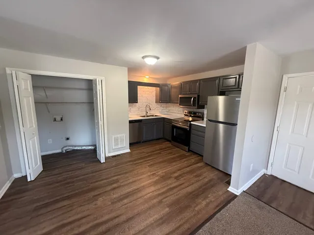 a kitchen with stainless steel appliances a refrigerator and wooden floor