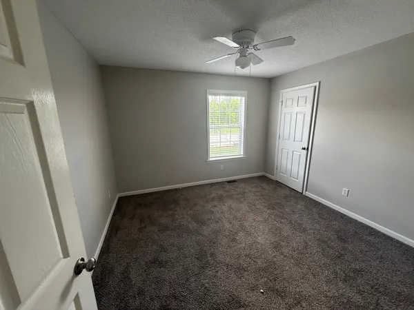 an empty room with windows and fan