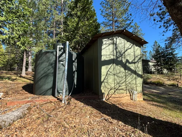 a view of a wooden house with a yard and large trees