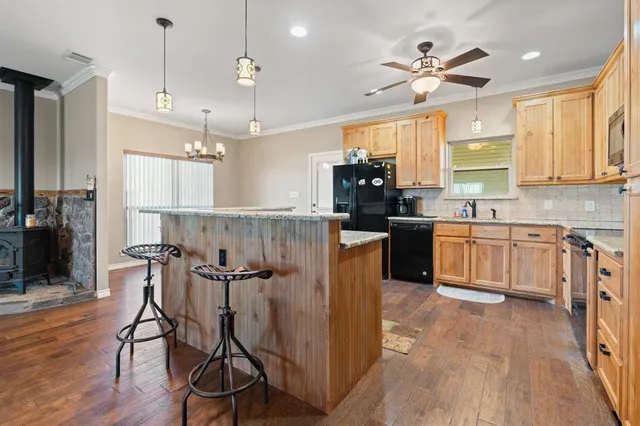 a kitchen with stainless steel appliances granite countertop a sink dishwasher a stove and a dining table with wooden floor