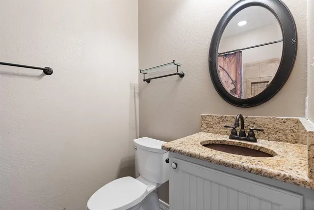 a bathroom with a granite countertop toilet sink and mirror