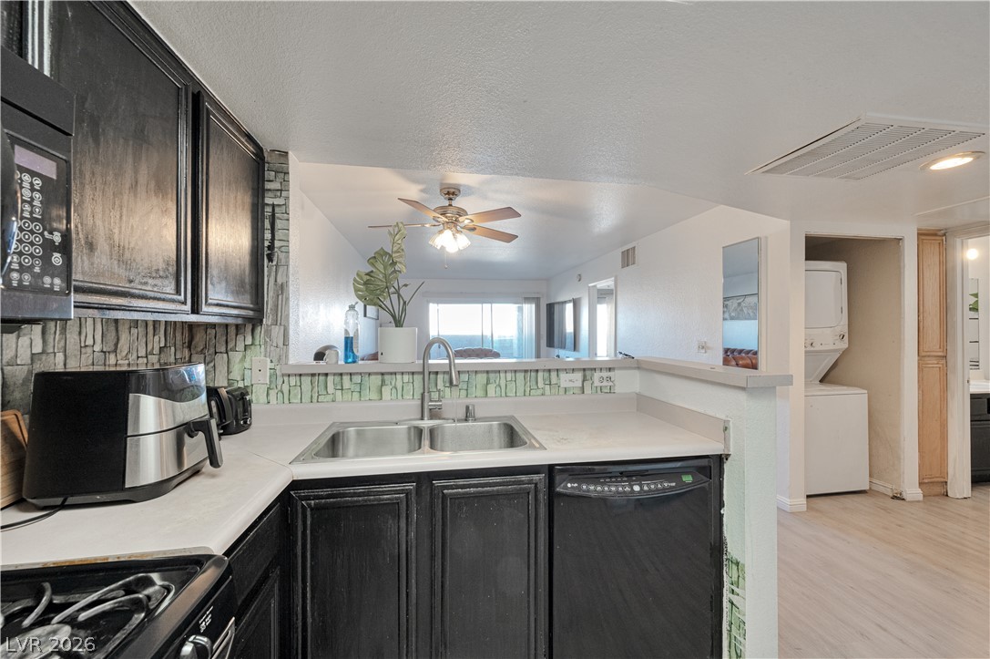 8025 West Russell Road, Unit 1090 Las Vegas, NV 89113 - Photo 2 of 23 Dark cabinetry and a breakfast bar opening to the living area define this kitchen.