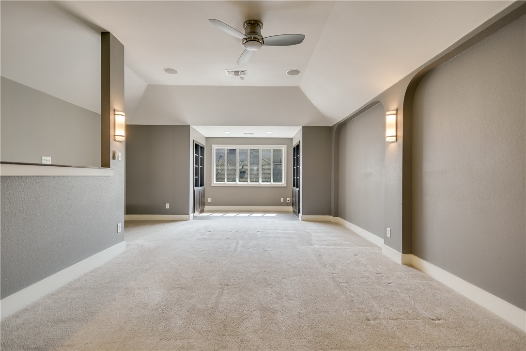 3513 Grimes Ranch Road Austin, TX 78732 - Photo 13 of 32 Empty room with a ceiling fan, light colored carpet, vaulted ceiling, and baseboards