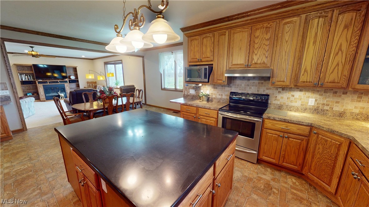 10323 Smith Road Litchfield, OH 44253 - Photo 13 of 50 Kitchen with decorative backsplash, under cabinet range hood, brown cabinets, and stainless steel appliances