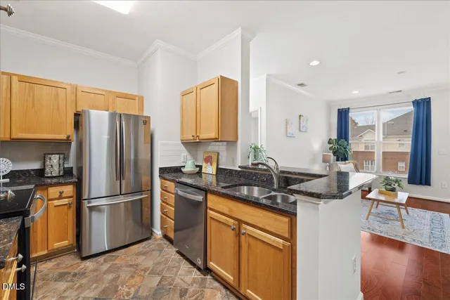 a kitchen with stainless steel appliances granite countertop a refrigerator a stove a sink a dining table and chairs with wooden floor