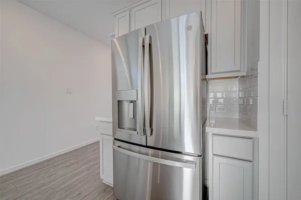 a view of a refrigerator in kitchen with stainless steel appliances wooden floor