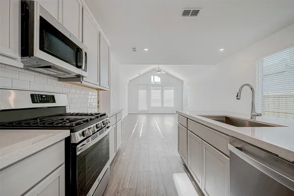 a kitchen with stainless steel appliances granite countertop a stove a sink and a microwave