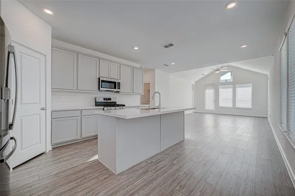 a kitchen with granite countertop a stove top oven a sink dishwasher and a refrigerator with wooden floor