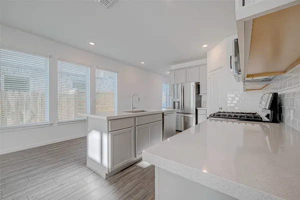 a large white kitchen with wooden floor and a sink