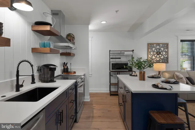 a kitchen with stainless steel appliances a sink dishwasher a stove and a dining table with wooden floor