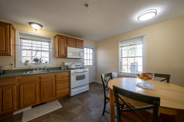 a kitchen with granite countertop a stove a sink dishwasher a dining table and chairs with wooden floor