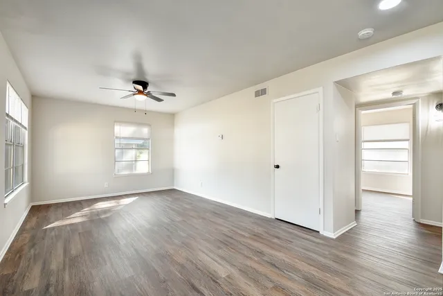 a view of an empty room with wooden floor and a window