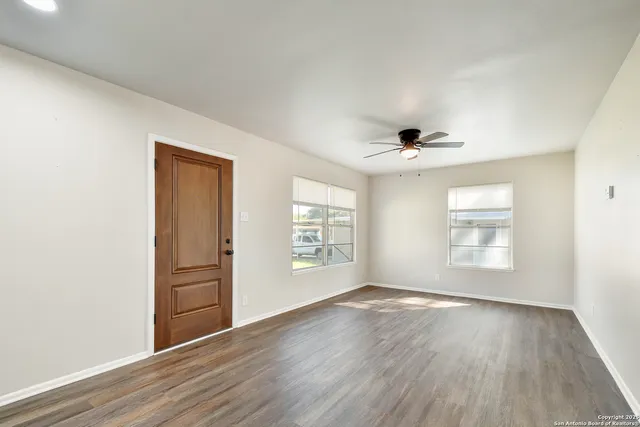 an empty room with wooden floor and windows