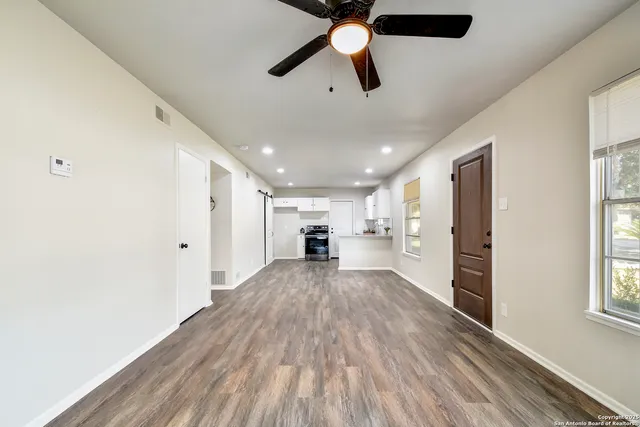 a view of a hallway with wooden floor and a window