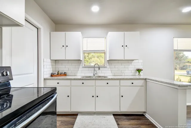 a kitchen with white cabinets and window