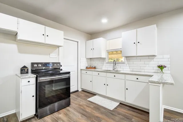 a kitchen with granite countertop white cabinets stainless steel appliances and sink