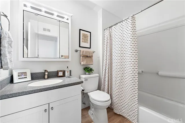 a bathroom with a granite countertop toilet a sink a mirror and a shower