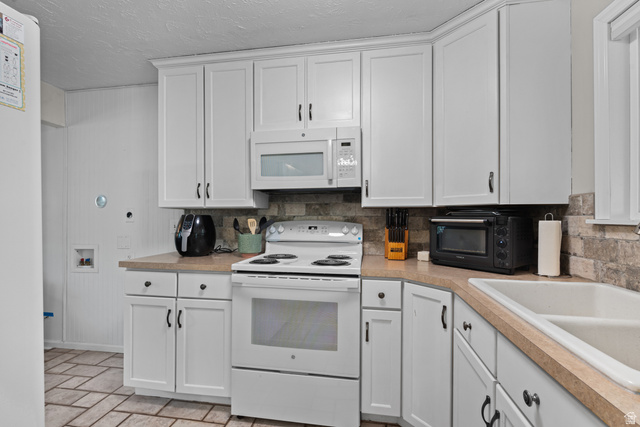 7659 State Street Midvale, UT 84047 - Photo 10 of 33 Kitchen featuring white cabinetry, light-colored countertops, a double basin sink, and a white electric range with an overhead microwave