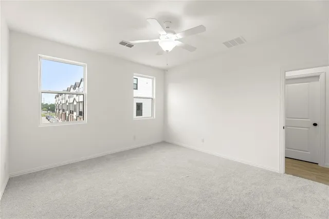 an empty room with windows and fan
