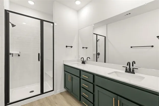 a bathroom with a double vanity sink a mirror and shower