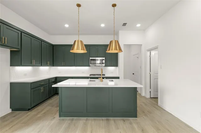 a kitchen with kitchen island granite countertop a sink a counter space and cabinets