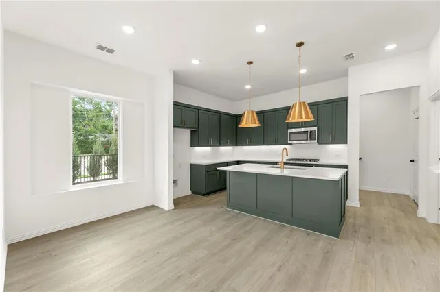a large kitchen with a large counter top a sink stainless steel appliances and cabinets