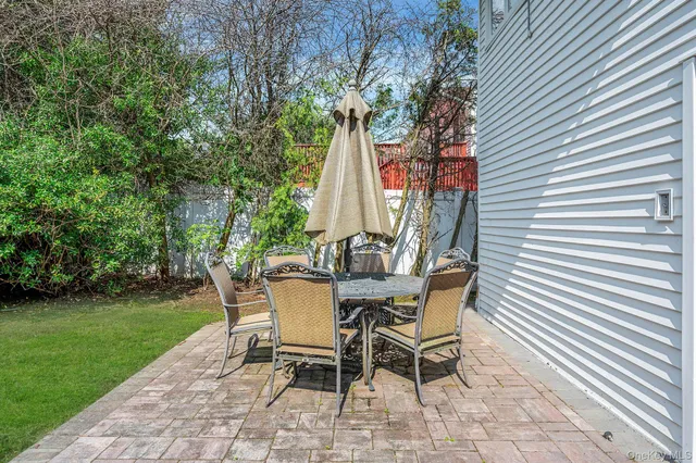 a view of a backyard with table and chairs and a barbeque with potted plants