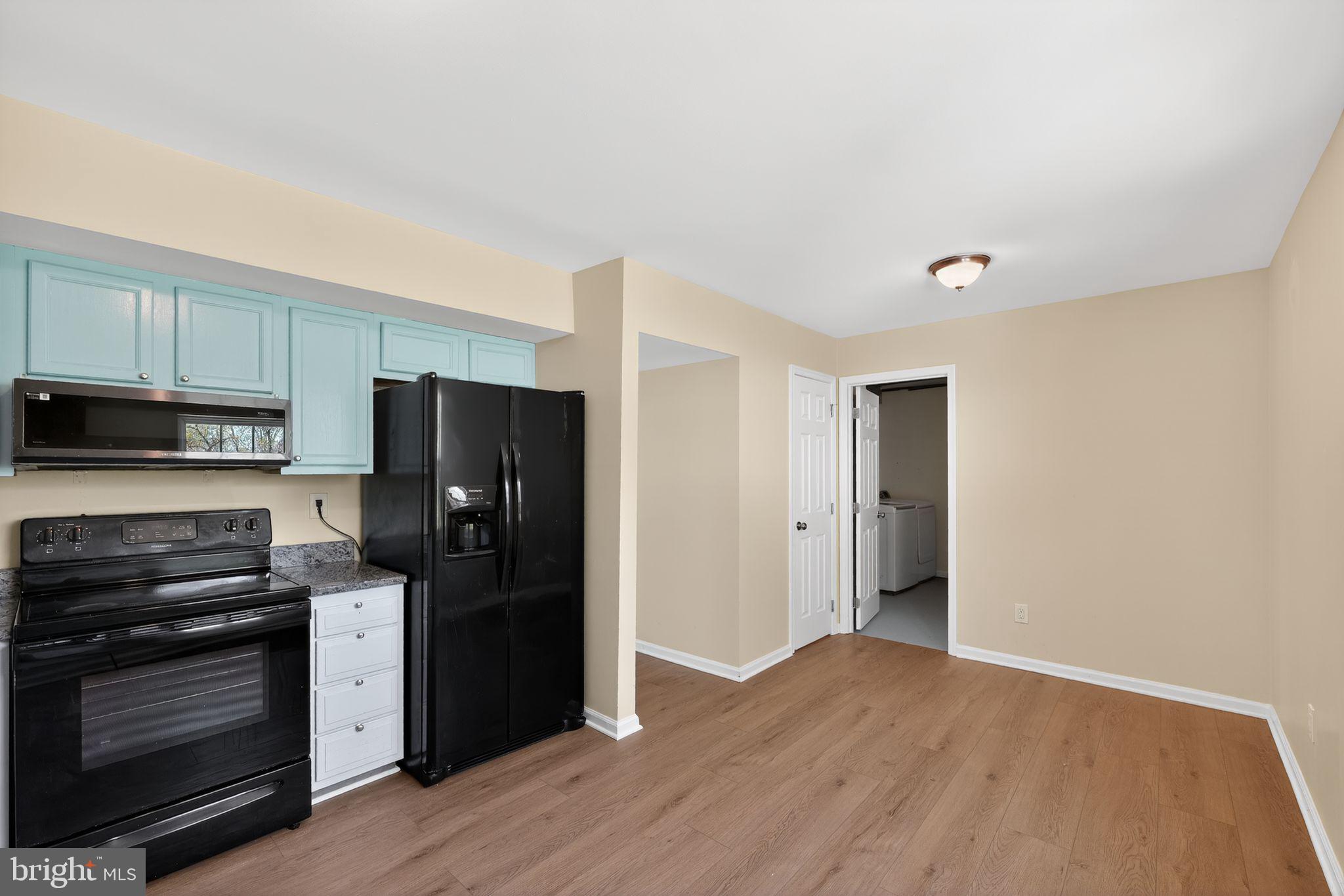 8090 Round Table Court Pasadena, MD 21122 - Photo 19 of 31 a kitchen with a refrigerator stove and wooden cabinets