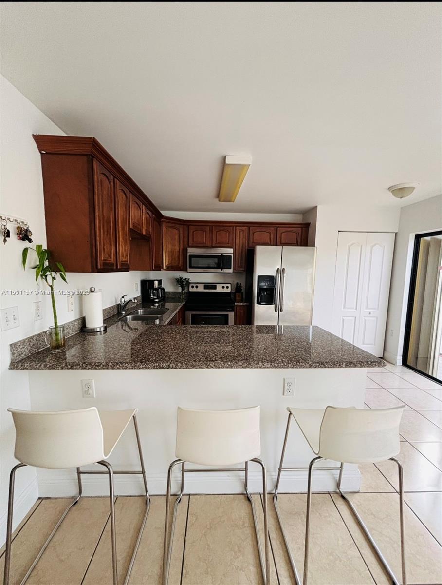 11115 West Okeechobee Road, Unit 181 Hialeah Gardens, FL 33018 - Photo 7 of 31 a kitchen with stainless steel appliances kitchen island granite countertop a table chairs in it and a window