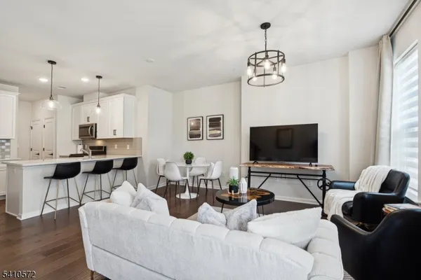 a living room with furniture a flat screen tv and kitchen view