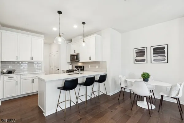 a kitchen with stainless steel appliances a dining table chairs and white cabinets