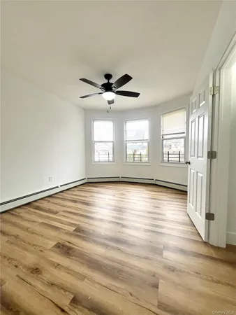 an empty room with wooden floor and windows with curtains