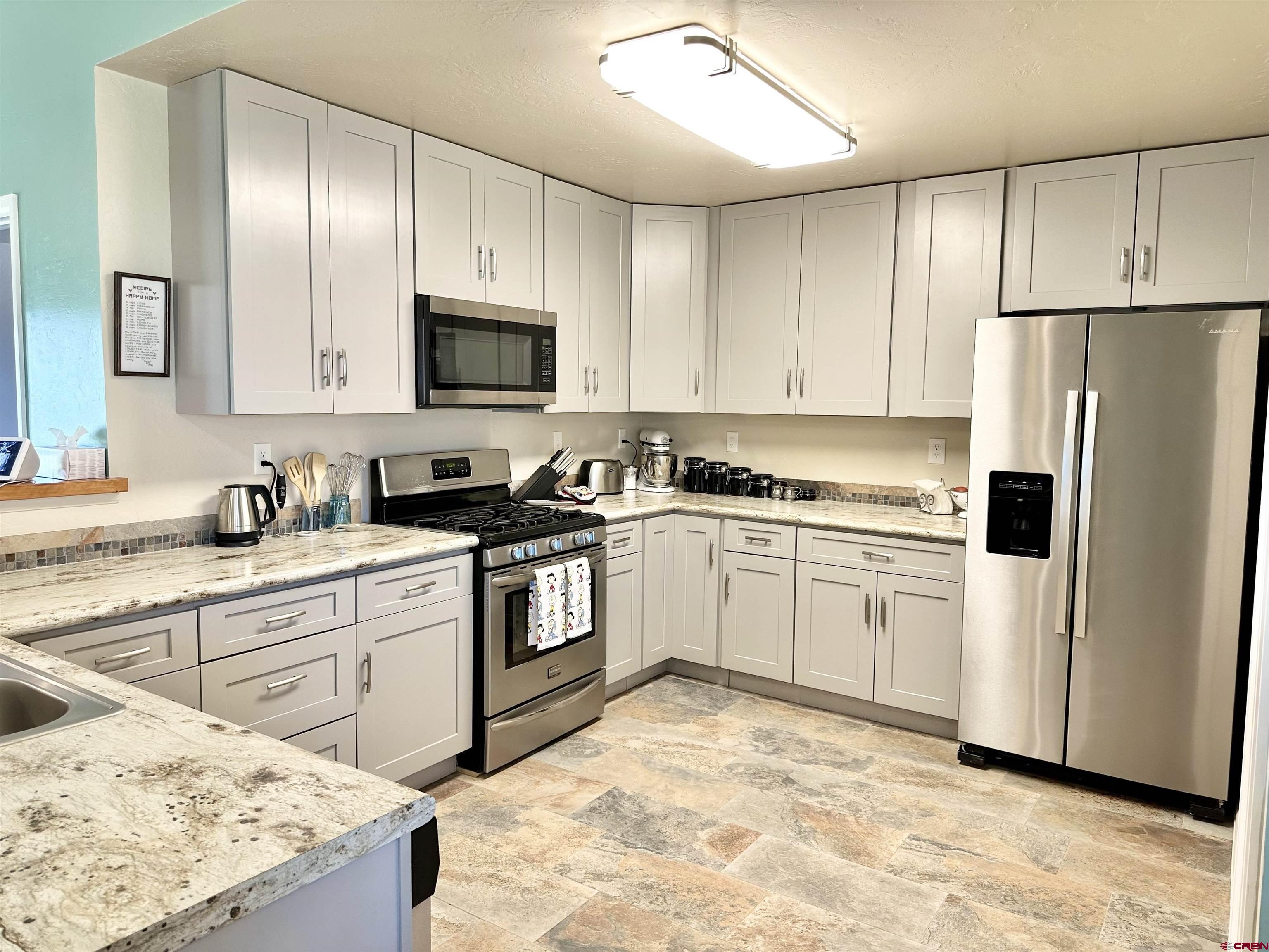 8352 2000th Road Austin, CO 81410 - Photo 14 of 35 a kitchen with granite countertop a refrigerator sink stove and white cabinets