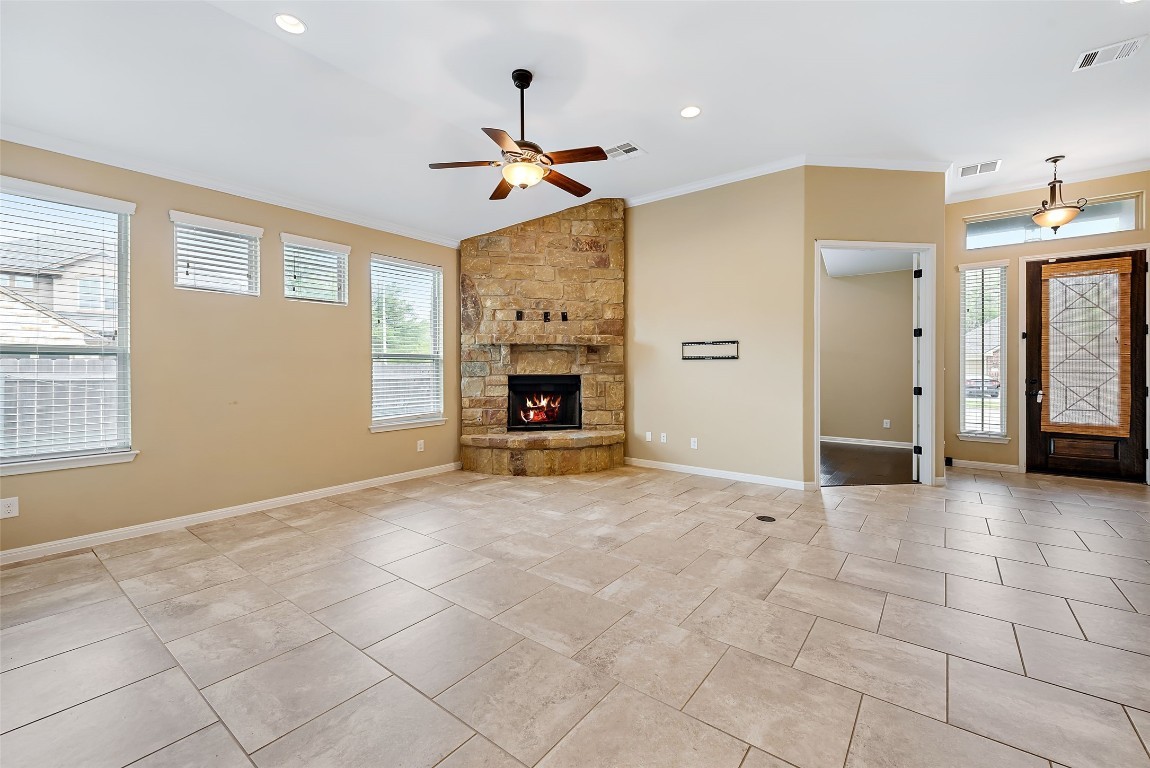 2000 Manada Trail Leander, TX 78641 - Photo 11 of 36 A spacious living room features a corner stone fireplace and light-toned tile flooring, creating a warm and inviting atmosphere.