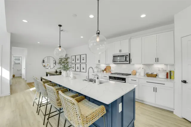 a kitchen with stainless steel appliances kitchen island granite countertop a dining table chairs and white cabinets
