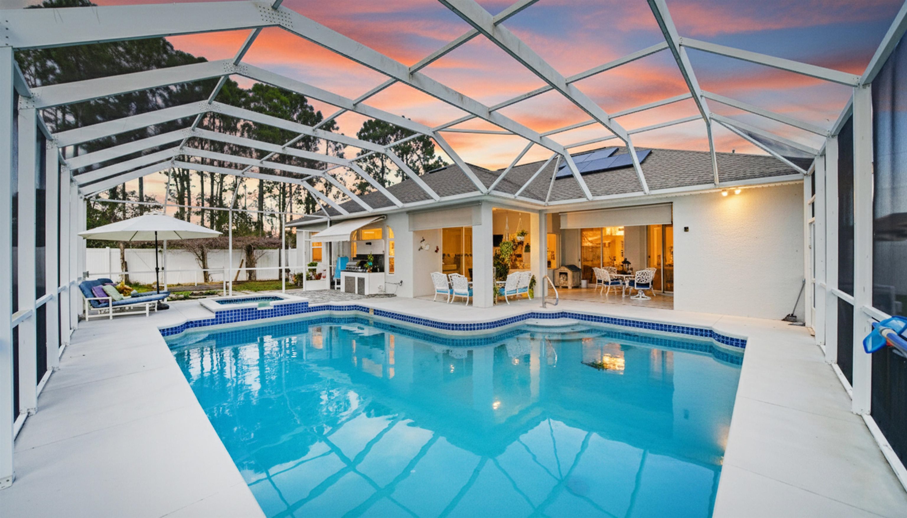 22 Flanders Lane Palm Coast, FL 32137 - Photo 2 of 70 Pool at dusk with a sunroom, a patio, a lanai, and a pool with connected hot tub
