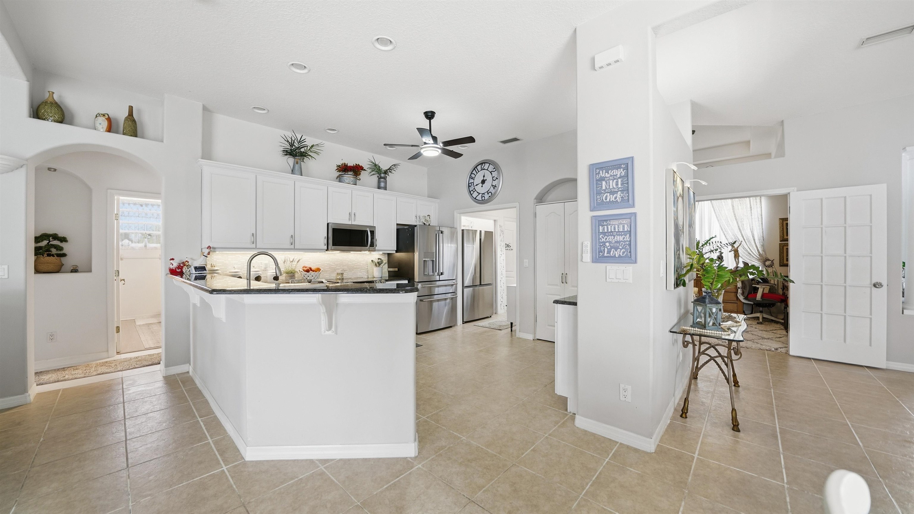 22 Flanders Lane Palm Coast, FL 32137 - Photo 28 of 70 Kitchen featuring a breakfast bar area, arched walkways, white cabinets, stainless steel appliances, and dark stone countertops