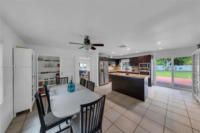 a kitchen with stainless steel appliances kitchen island granite countertop a table chairs and a refrigerator