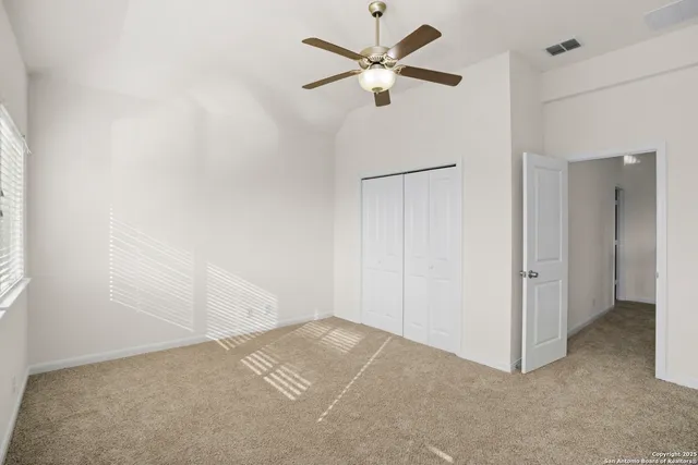 an empty room with a ceiling fan and a window