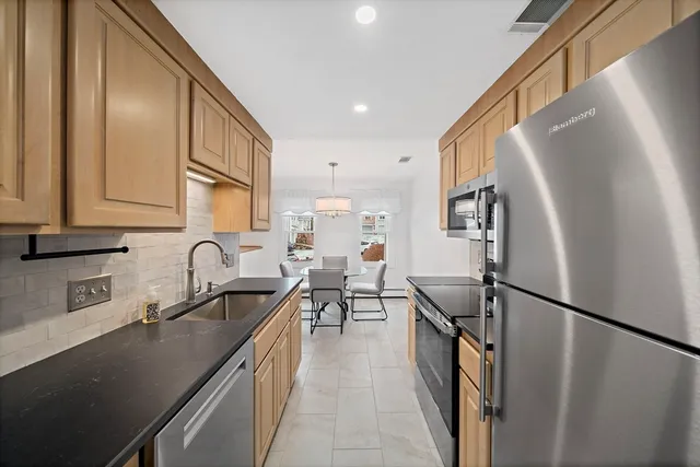 a kitchen with stainless steel appliances granite countertop a sink refrigerator and cabinets
